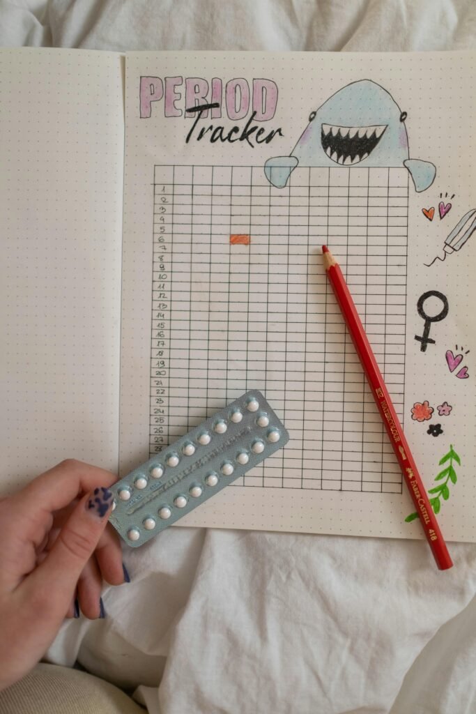 Creative period tracker notebook with a hand holding birth control pills.